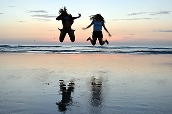 Two girls jumping on beach