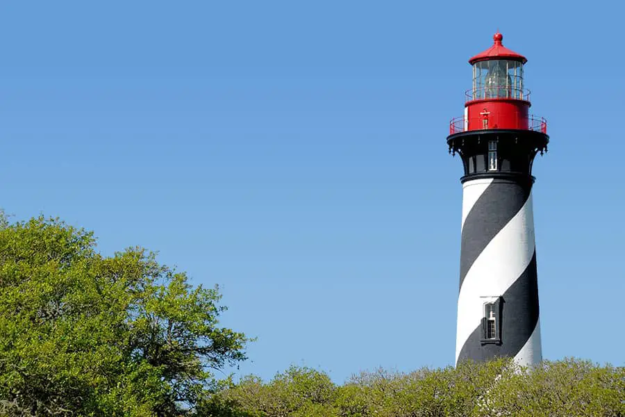 Red and white lighthouse above the tree line at St Augustine