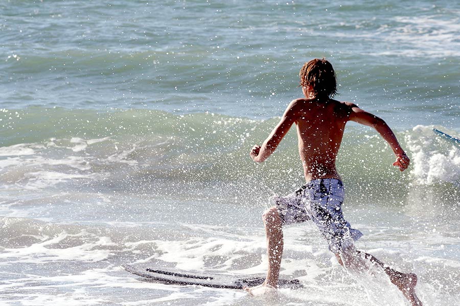 Young skimboarder running to jump on board