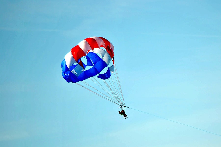 Couple parasailing high above the ocean, towed behind a boat