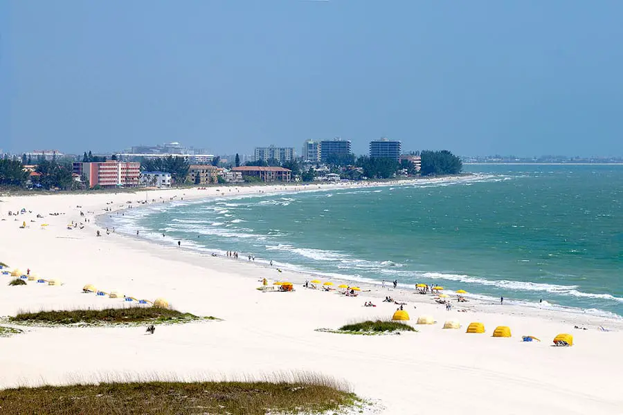 People on the white sand at Treasure Island beach, skyscrapers in the horizon