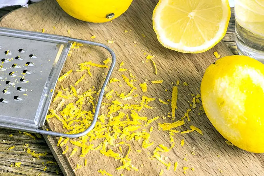 Metal grater removing the zest from lemons