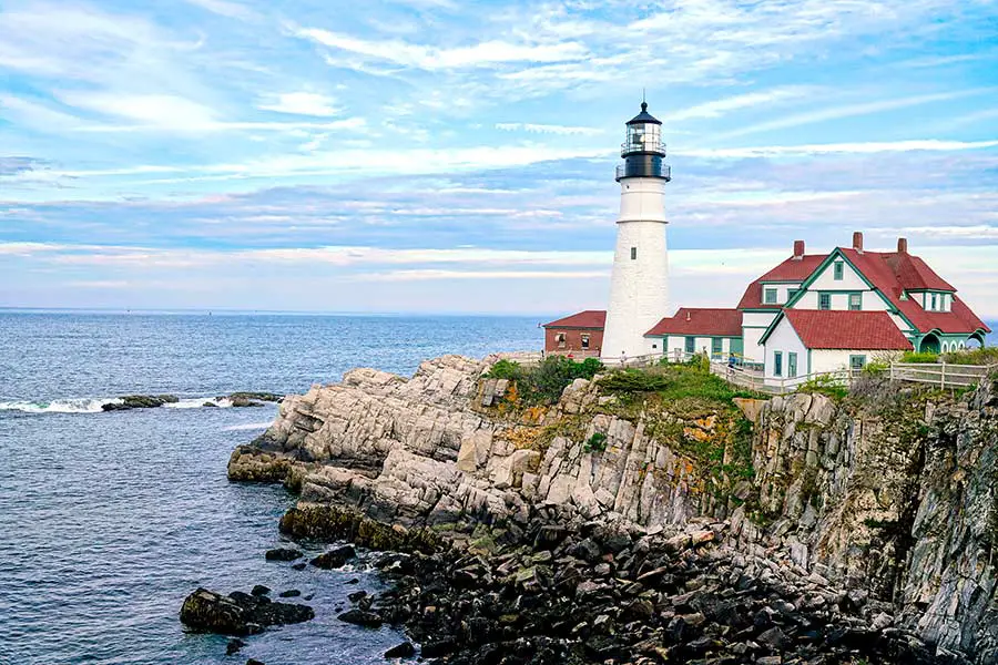 White lighthouse and lightkeepers house sit atop a rocky coastline, Portland Maine