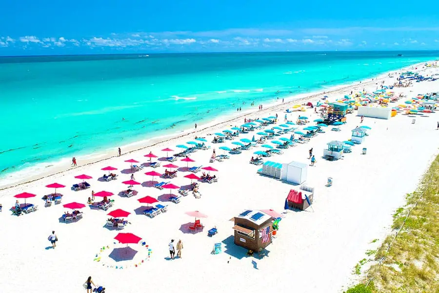 Red and blue Canopy chairs dot the beach at South Beach, Miami