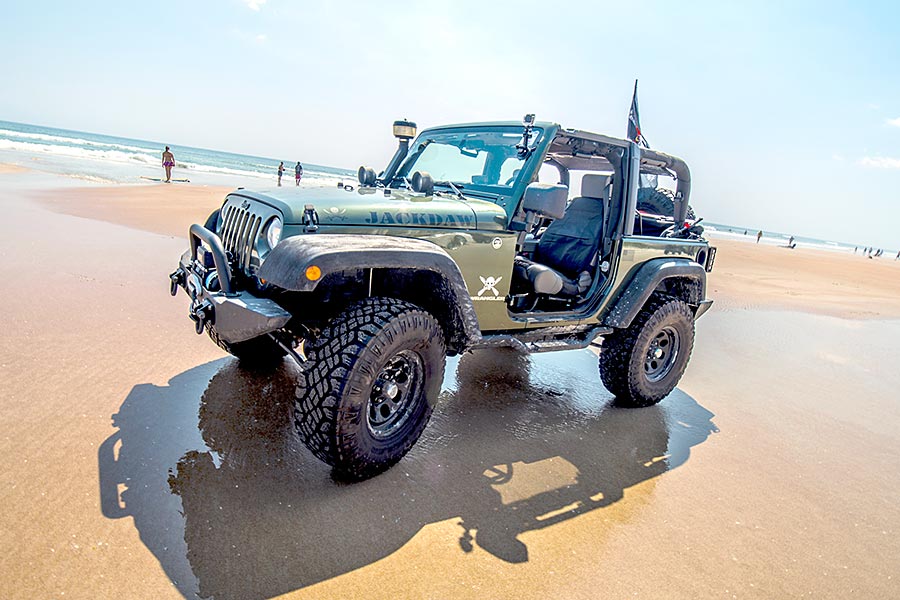 Green Jeep 4x4 sitting on the sand at Daytona Beach
