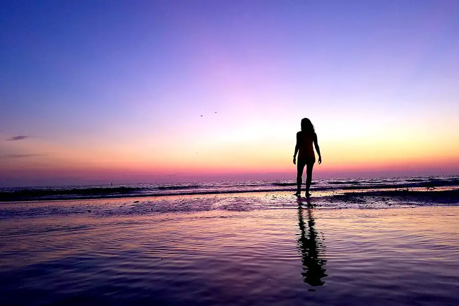 Silhouette of woman standing on the beach at sunset