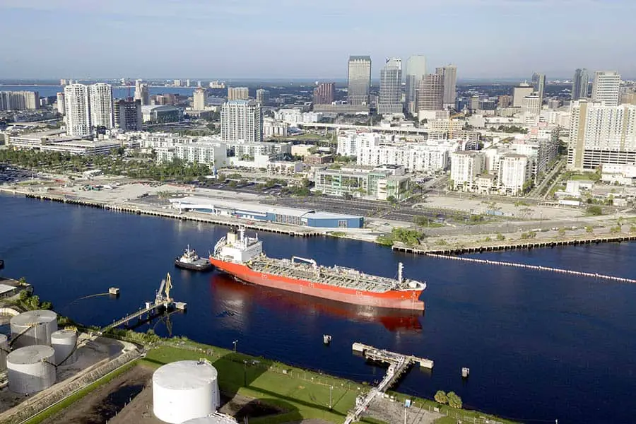 Tug boat helping large cargo ship through channel