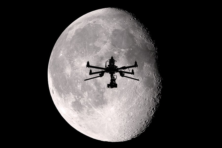 Silhouette of drone in front of moon