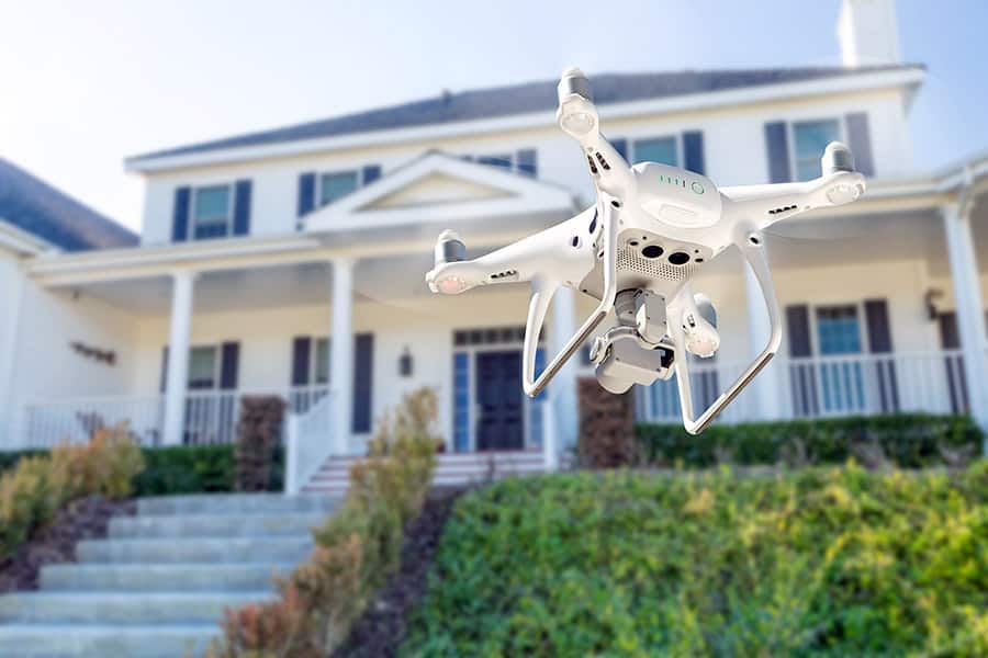 White drone photographing house