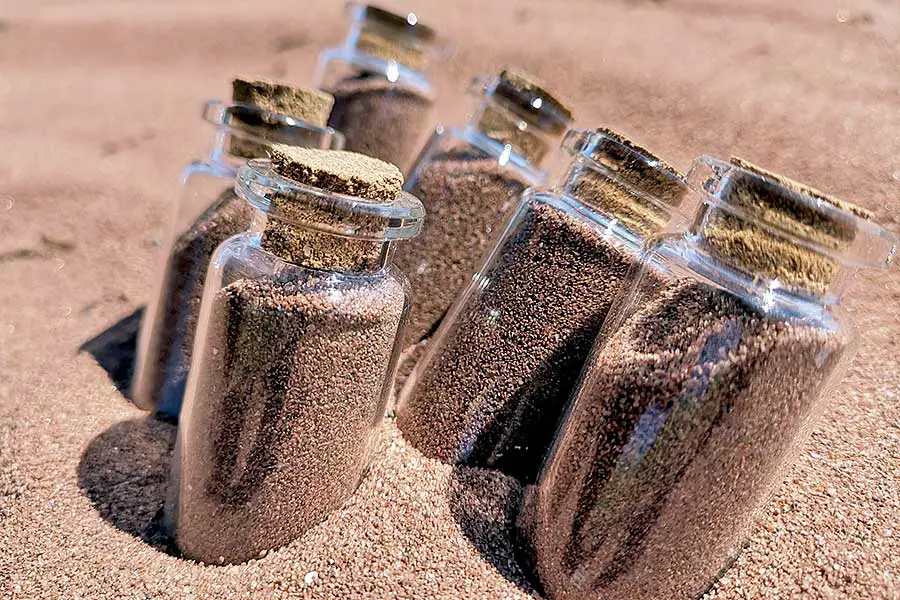 Six jars with cork stoppers filled with brown sand