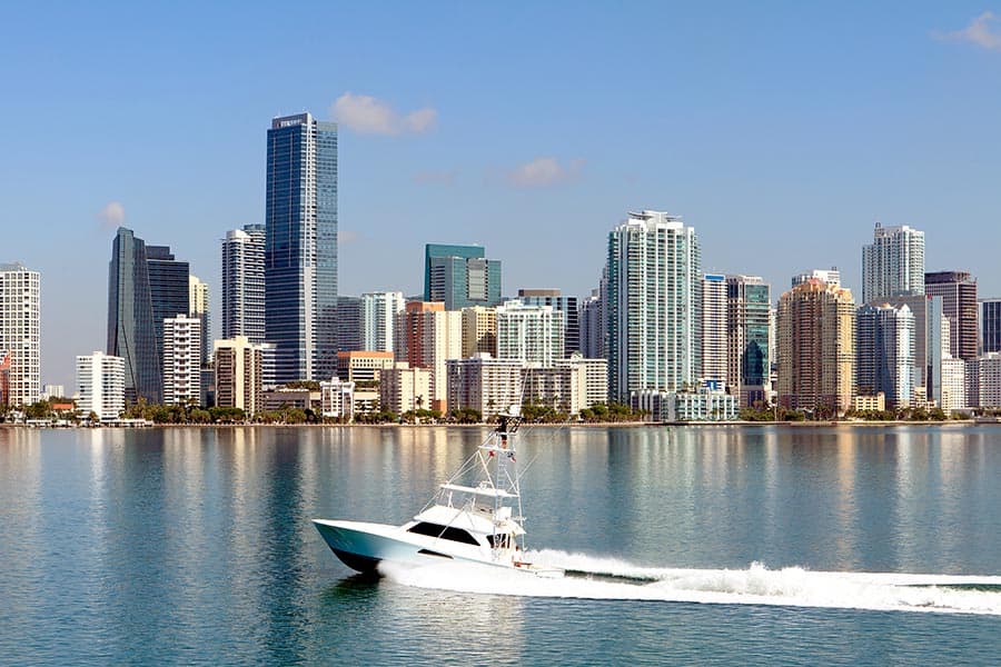 Fishing boat speeding across Biscayne Bay, city skyscrapers at waters edge