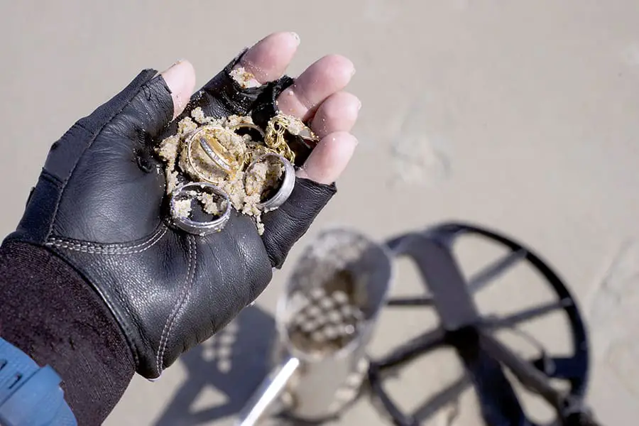 Man metal detecting on beach finds rings and jewelry
