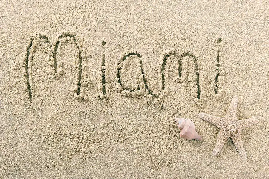 A starfish and seashell on beach along side Miami sand writing