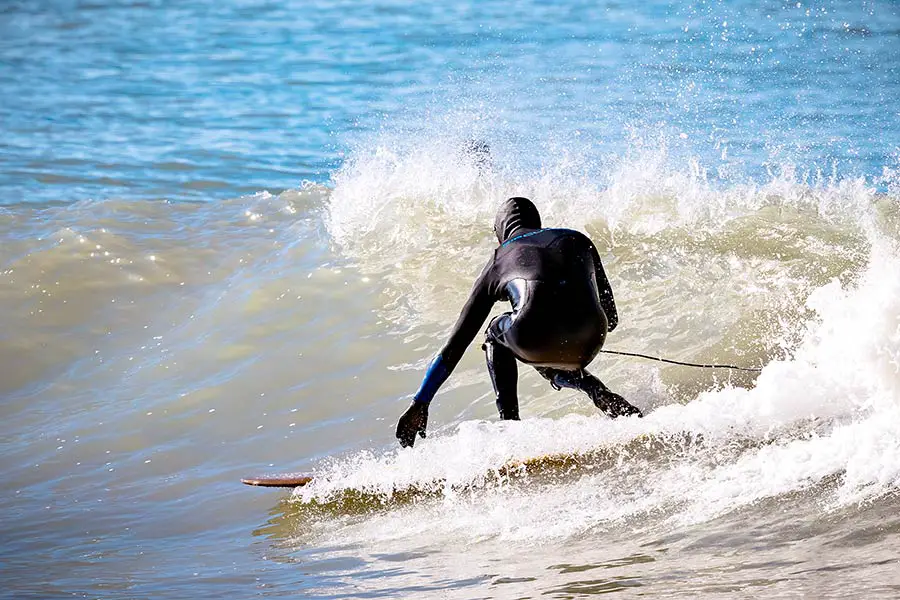 Surfer dressed in wet suit riding small wave