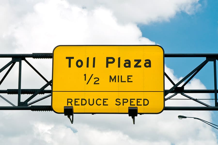 Yellow sign above highway, toll plaza one half mile ahead