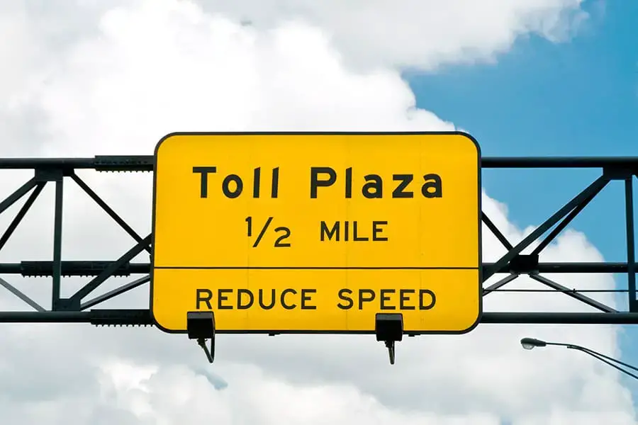 Yellow sign above highway, toll plaza one half mile ahead